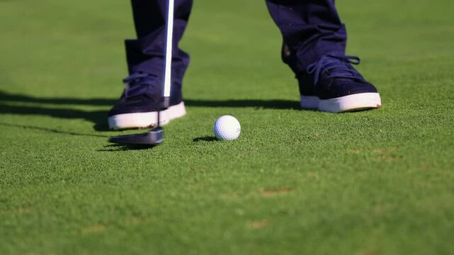 Close-up of a golf ball being hit by a putter on the golf course