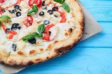 Pizza with mozzarella cheese , olives , chicken , pineapple , basil and tomatoes