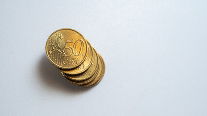 A close-up of a 50 euro cent coin on a white background. The bright gold color and shallow depth of field make the details of the coin, such as the embossed numbers and the map, stand out. Perfect for