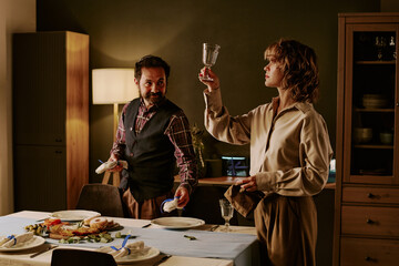 Jewish husband looking at his beloved wife while she checking glass cleanness