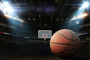Basketball ball on the floor in a basketball arena with hoop and floodlights, concept. Basketball championship, creative idea. Winning. Sport card basketball tournament
