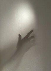 The shadow of a human hand reaching out to grab the light