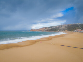 Breaking waves at Nazare beach on the Portugal coastal town on the Atlantic ocean shore. Aerial drone view