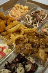 Seafood antipasti. Top view of a large box with different dishes such as fried squid rings and shrimps, octopus and squid mussels with provencal, salads, pickles and shrimp cocktail