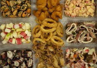 Finger food. Top view of a seafood antipasti dish with preparations such as fried squid rings, shrimps, calamarettes, mussels, squid and octopus with provencal, show salad with kani kama and pickles