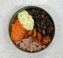 Healthy salad. Top view of a bowl with a salad made with tuna fish, cucumber, carrot, cherry tomatoes and purple lettuce