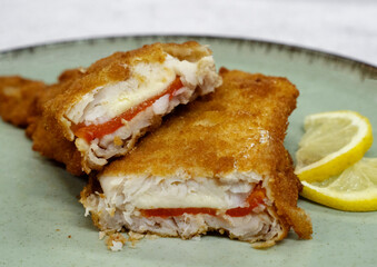 Mediterranean food. closeup view of a sliced battered hake filet stuffed with melted mozzarella cheese and red bell pepper