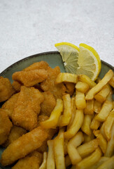 Seafood. Top view of a bowl with fried fish nuggets, lemon slices and potatoes with a white background