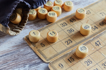 Tokens from a bingo bag cover the numbers on old yellowed vintage cards, home bingo game, traditional retro board game, vintage money game.