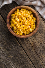 Canned sweet corn in bowl on wooden table. Top view.