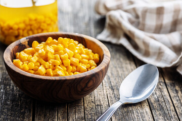Canned sweet corn in bowl on wooden table.