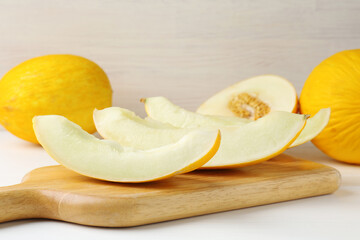 Whole and cut ripe melons on white table