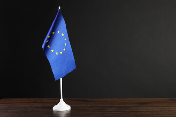 One flag of European Union on wooden table against black background. Space for text