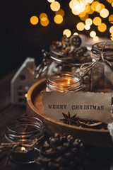 Home aromatherapy. Aroma candles with pine extract, spruce cone, cinnamon, anise, vanilla scent, candles, wooden table. Cozy atmosphere, winter inspiration, knitted sweater. Merry Christmas note