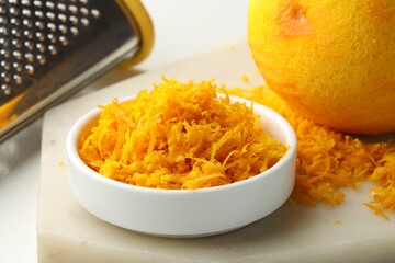 Fresh orange zest, grater and fruit on light table, closeup