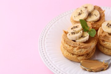 Tasty sandwiches with peanut butter, banana, chia seeds, mint and spoon on pink background, closeup. Space for text