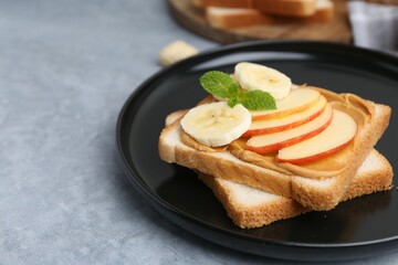 Tasty sandwich with peanut butter, apple, banana and mint on grey table, closeup