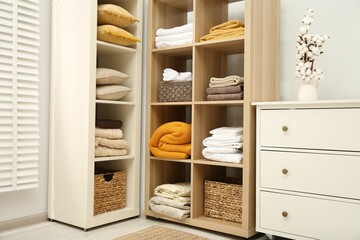 Home textile organization. Folded towels, blankets and pillows on shelving units indoors