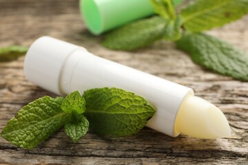 Natural lip balm and mint leaves on wooden background, closeup