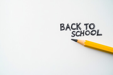 Bright yellow pencil next to back to school text on white background