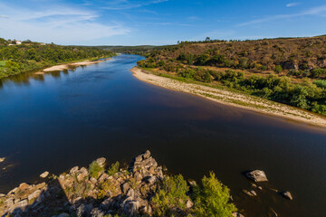 winding river bordered by sandy banks and lush vegetation