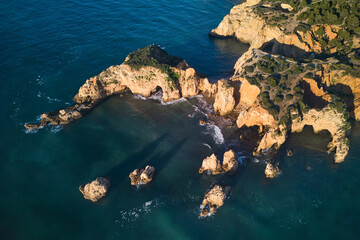 Top-down view of the limestone cliffs with grottoes washed by the ocean. Algarve, Portugal