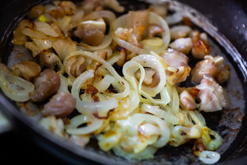 Small pieces of pork and shredded onion being fried in iron skillet