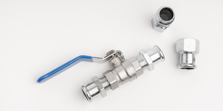 Water valve with blue handle and hydraulic fittings lying on a white background (selective focus)