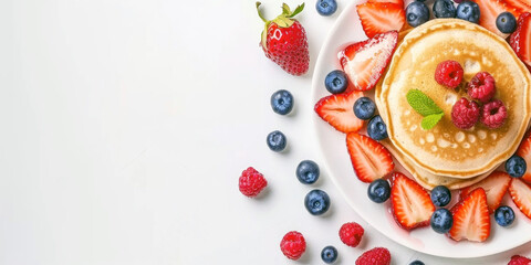 A tempting stack of fluffy pancakes is garnished with vibrant strawberries, blueberries, and raspberries. Bright mint leaves add a fresh touch, making this dish the perfect breakfast or brunch option