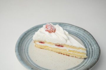 One small Japanese strawberry shortcake on a stylish Japanese plate on a white table