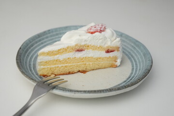 One small Japanese strawberry shortcake and a small fork on a stylish Japanese plate on a white table