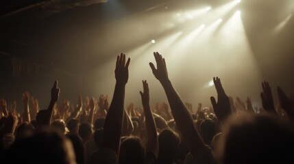 Fototapeta premium A sea of arms reaches skyward as a crowd basks in the glow of stage lights, capturing the electrifying essence of a live concert.