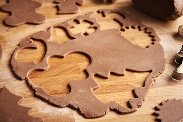 Cutting out shapes from rolled out raw pastry dough to prepare gingerbread Christmas cookies
