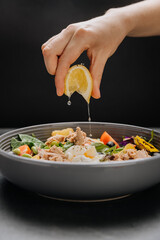 Fresh lemon juice squeezed over a nutritious tuna salad with poached egg, greens and vegetables