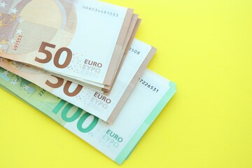 Big amount of one hundred and fifty euro money bills on yellow background