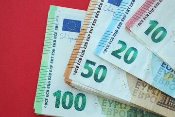 Big amount of one hundred, twenty, ten and fifty euro money bills on red background