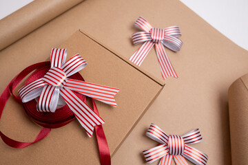 Obraz premium Wrapping and wrapping Christmas gifts, surprises in kraft paper close-up. Satin ribbons and bows for decoration. Gift for the holiday, surprise. Gifts for Boxing Day