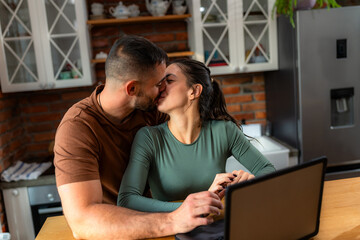 Couple shares an intimate moment together in their home kitchen, pausing from their daily tasks to connect with one another.