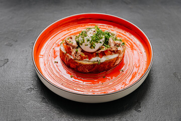 Delicious gourmet toast topped with poached egg, tuna, and fresh herbs on vibrant orange plate