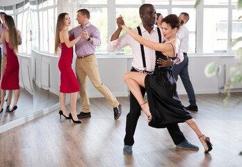 Active middle-aged lady training waltz in pair with man in dance-hall during dancing classes