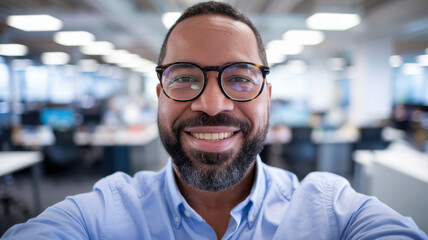 A smiling African American man in a light blue shirt, showcasing a friendly demeanor in a modern office environment.