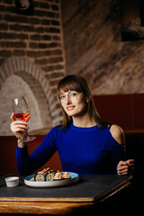 Woman enjoying sushi with wine in a stylish restaurant, creating a refined dining experience