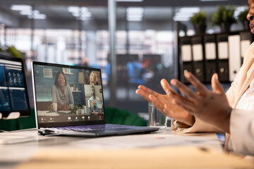 Businesswoman with employees in videocall, using laptop in office. Close up of entrepreneur...