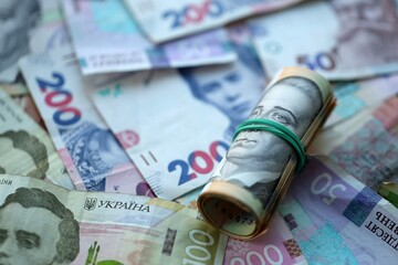 Roll of 500 Ukrainian Hryvnia money bills lies on big pile of ukrainian currency money close up
