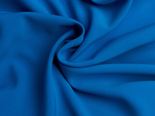 Blue fabric lies in beautiful folds. High-quality texture of blue fabric.