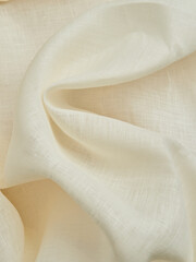 Beautiful folds of beige linen fabric. High-quality texture of beige linen fabric.