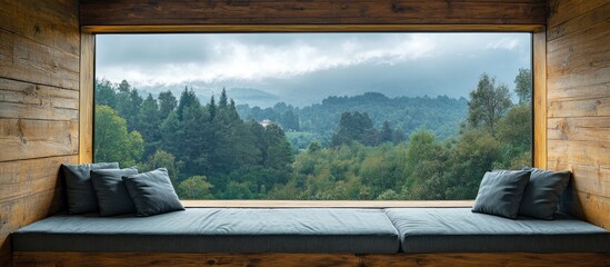 Rustic wooden wall with a large window showcasing a stunning view of the forest under cloudy skies