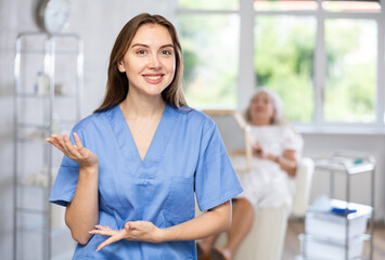 Portrait of young female doctor standing while senior woman checking procedure results in the back.