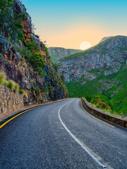 Vertical view of sun setting behind the mountain on a winding road through Langeberg Mountains, Suurbraak, Overberg, Western Cape, South Africa