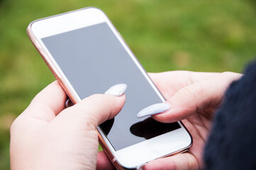 Typing sms. Close up view of young woman using her smart phone in the park